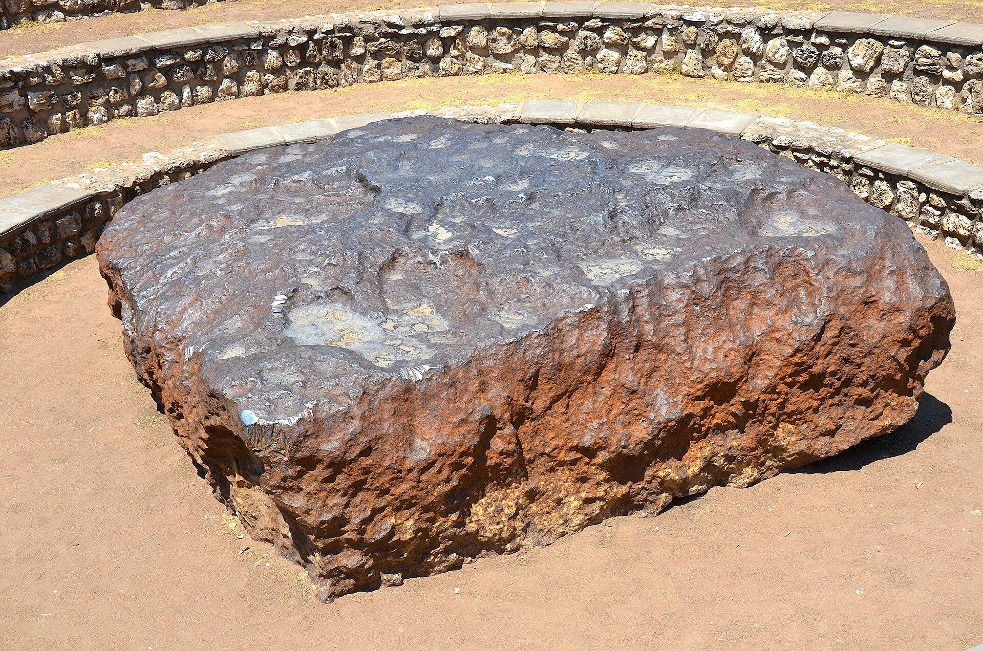 The flat, rust-brown Hoba meteorite inside its circular stone amphitheatre